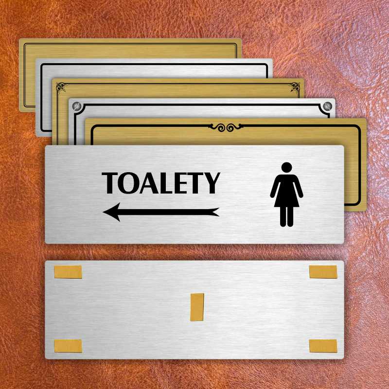 Toalety vlevo ženy, 240x79mm, zlatá popiska s okrasným rámečkem  
